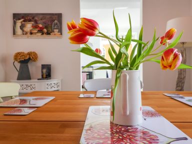 A dining table with a vase of red and yellow tulips and placemats at The Corner House in Ufford near Woodbridge