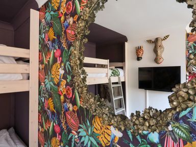 A bedroom with bunk beds a TV mounted on the wall and animal head decorations at The Corner House in Ufford near Woodbridge