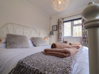 A bedroom with a bed with gray pillows and brown towels on a knitted blanket at The Corner House in Ufford near Woodbridge
