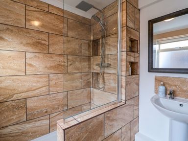 A bathroom with a bathtub shower combination and a sink with a mirror at The Corner House in Ufford near Woodbridge