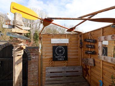 An outdoor wooden seating area with nautical decorations and signs at The Corner House in Ufford near Woodbridge