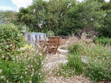 A garden with wooden chairs and flowers at The Corner House Ufford near Woodbridge