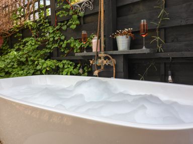 A bathtub with bubbles near plants and glasses at The Corner House in Ufford near Woodbridge