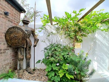 A garden with a knight statue and various plants at The Corner House Ufford near Woodbridge