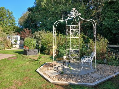 A gazebo with a chair and table in the garden at The Corner House in Ufford near Woodbridge