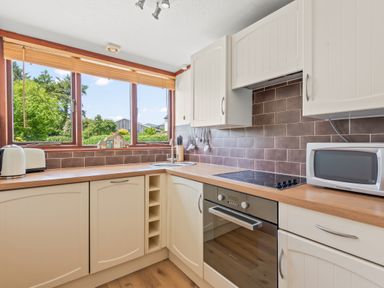 A kitchen with white cabinets wooden countertops a microwave toaster and an electric stove at The Dairy in St Neot