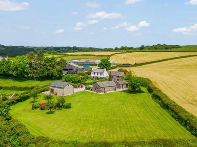 Aerial view of a rural property with stone buildings green lawns and surrounding fields at The Dairy in St Neot