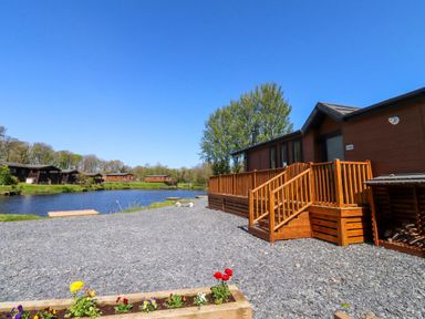 An outdoor area with a lodge and deck near a river at Lakeside Lodge Bowland Lakes Leisure Village near Garstang