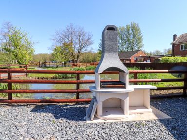 An outdoor barbecue area near a pond at Lakeside Lodge Bowland Lakes Leisure Village near Garstang