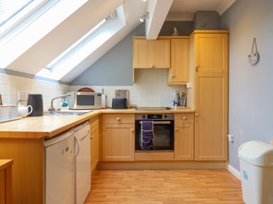 A kitchen with wooden cabinets a built-in oven a microwave a kettle and two skylight windows at 5 Lakeview Rise in Highampton near Hatherleigh