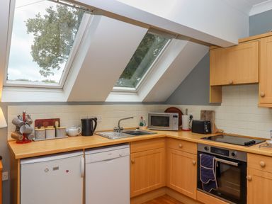 A kitchen with wooden cabinets and countertops under slanted windows at 5 Lakeview Rise in Highampton near Hatherleigh
