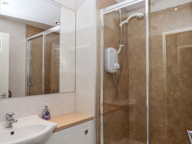 A bathroom with a sink and mirror next to a shower with glass doors at 5 Lakeview Rise in Highampton near Hatherleigh