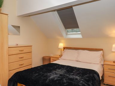 A bedroom with a bed bedside tables lamps a chest of drawers and a skylight window at 5 Lakeview Rise in Highampton near Hatherleigh
