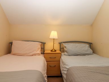 A bedroom with two single beds separated by a wooden nightstand with a lamp on top at 5 Lakeview Rise Highampton near Hatherleigh