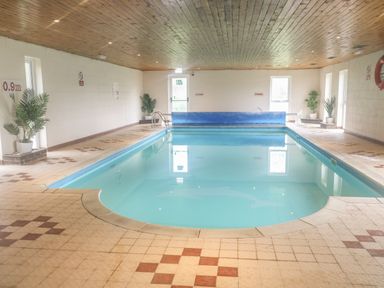 An indoor swimming pool with tiled floor and wooden ceiling at 5 Lakeview Rise in Highampton near Hatherleigh