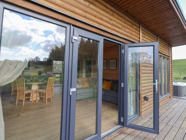 A wooden house exterior with glass door open showing dining table and chairs inside at Foxglove in Higher Wambrook near Chard