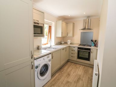 A kitchen with built in appliances including a washing machine oven microwave and gas stove at Bwthyn Clyd in Llanddaniel Fab