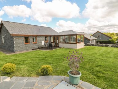 A stone house with a small patio and garden with a potted plant at Bwthyn Clyd in Llanddaniel Fab