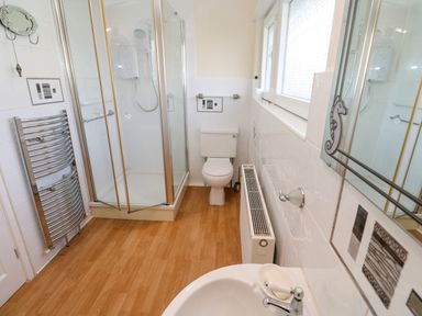 A bathroom with a shower cubicle a toilet a sink and a radiator at Karenza in Penzance