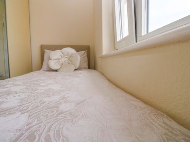 A bed with a pillow near a window at Karenza in Penzance