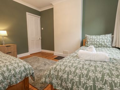 A bedroom with two single beds a bedside table with a lamp and a rug on a wooden floor at Honeypot Cottage in Swanage