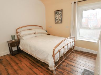 A bedroom with a double bed metal frame bedside tables and wooden floor at Honeypot Cottage in Swanage