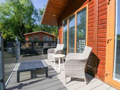 A deck with chairs and a table at Dovedale Lodge Troutbeck Bridge