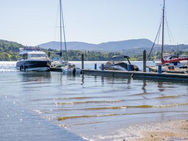 Boats at a dock on water with mountains in the background at Dovedale Lodge in Troutbeck Bridge
