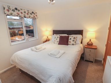 A bedroom with a bed and bedside tables at Dovedale Lodge Bowness 70 White Cross Bay near Windermere