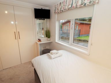 A bedroom with a bed, cupboard, and television at Dovedale Lodge Bowness 70, White Cross Bay near Windermere