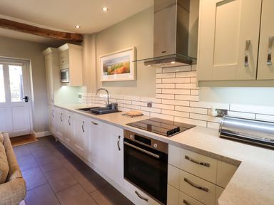 A kitchen with white cabinets a stove oven and a sink at Fox Howe in Thornthwaite