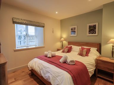 A bedroom with a double bed bedside tables lamps and a window at Fox Howe in Thornthwaite