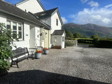 An outdoor view of a house with a bench and flower pots at Fox Howe in Thornthwaite
