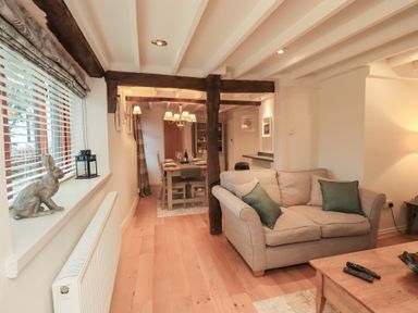 A living room with a sofa and dining area at Jasmine Cottage in Thornthwaite