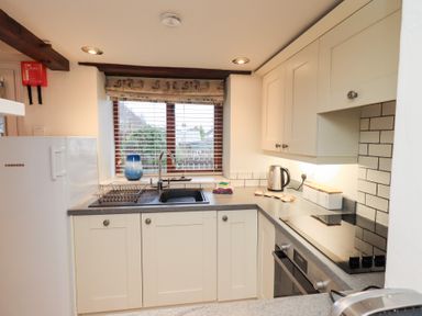 A kitchen with a fridge, sink, and stove at Jasmine Cottage in Thornthwaite