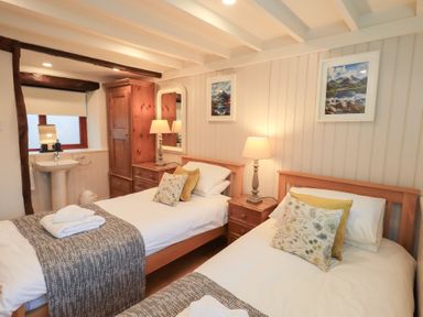A bedroom with two beds and a washbasin at Jasmine Cottage in Thornthwaite