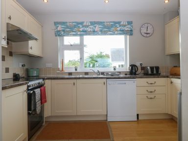 A kitchen with cream cabinets and brown countertops a stove dishwasher and kitchen appliances at Ty Nant in Abersoch