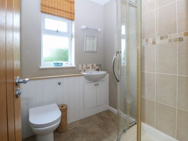 A bathroom with a toilet sink shower and window at Ty Nant in Abersoch