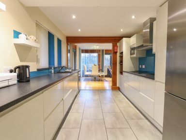 A kitchen with black countertops white cabinets and a dining area in the background at Tealby in Horning