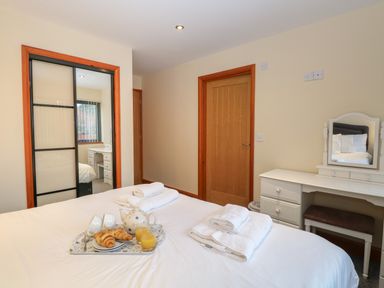 A bedroom with a bed with breakfast tray towels a vanity table and a door at Tealby in Horning