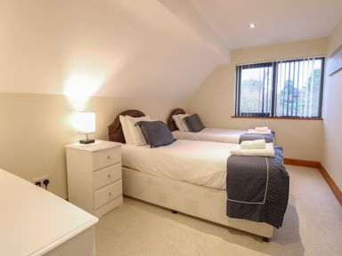 A bedroom with two single beds a bedside table with a lamp a window and towels on the beds at Tealby in Horning