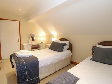 A bedroom with two single beds bedside tables and a dressing table with a mirror at Tealby in Horning