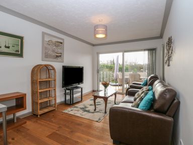 A living room with a brown leather sofa a coffee table and a television on a stand at White Gables in Horning
