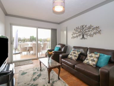 A living room with brown leather sofas a coffee table and a metal tree wall decoration at White Gables in Horning