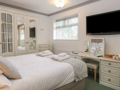 A bedroom with a bed matching furniture and a wall mounted television at White Gables in Horning