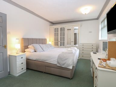 A bedroom with a bed pillows and folded towels beside a wardrobe and a chest of drawers at White Gables Horning
