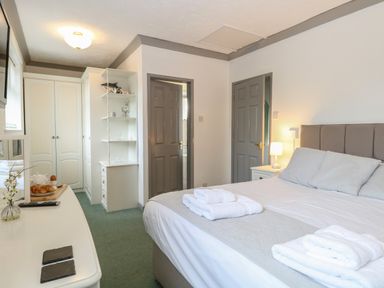 A bedroom with a double bed folded towels bedside table lamp wardrobe and a white dressing table at White Gables in Horning