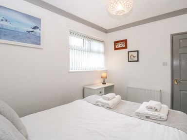 A bedroom with a bed towels on it a bedside table with a lamp paintings on the walls and a window at White Gables in Horning