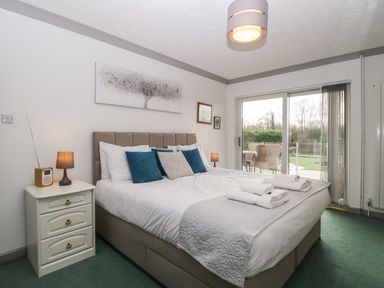 A bedroom with a large bed and bedside tables next to a sliding glass door at White Gables in Horning