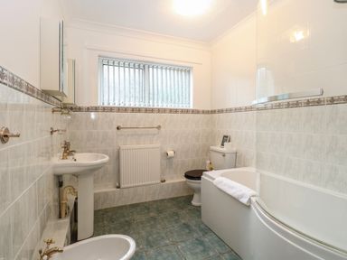 A bathroom with a bathtub sink toilet bidet and tiled walls and floor at White Gables in Horning